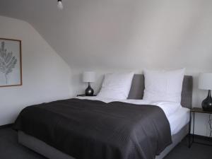 1 dormitorio con 1 cama grande con sábanas y almohadas blancas en Ferienhaus Joos, en Uhldingen-Mühlhofen