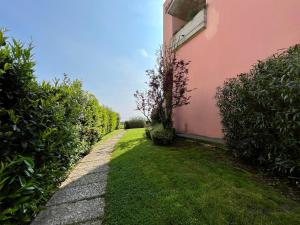 a walkway next to a pink building with bushes at Residence Virgilio in Sirmione