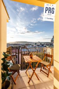 een balkon met een tafel en stoelen en uitzicht op de stad bij TurnKey I Angelo Roma Apartments in Praag
