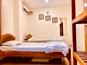 two twin beds in a room with white walls at Hotel Devika in Dibrugarh +12 photos