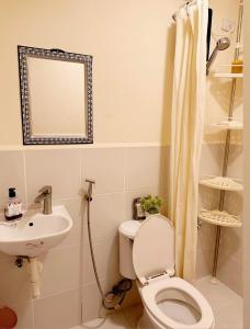 a bathroom with a toilet and a sink and a mirror at Katas ng Japan Staycation Studio Unit in Manila