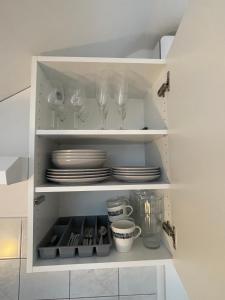 un armario blanco con platos y copas de vino en Apartments Park Vodice - Ljubljana, Krvavec, en Woditz