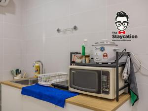 eine Küche mit Mikrowelle und Spüle in der Unterkunft Staycation Homestay 34 Kuching Riverine Petanak Resort in Kuching