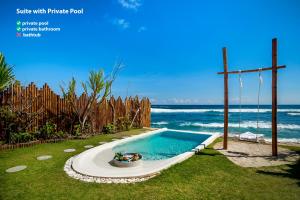 una pequeña piscina con una cruz de madera junto al océano en Bubble Hotel Nyang Nyang - Adults only, en Uluwatu