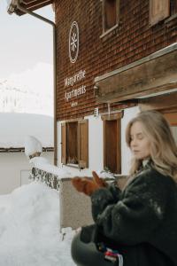a woman sitting in the snow in front of a building at Margarethe Apartments Lech in Lech am Arlberg