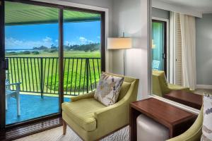 Cette chambre d'hôtel dispose d'un balcon avec un bureau et des chaises. dans l'établissement OUTRIGGER Kaua'i Beach Resort & Spa, à Lihue