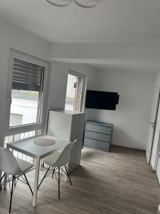 Habitación blanca con mesa, sillas y TV. en Neckar-Apart, en Heilbronn
