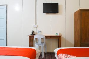 a room with two beds and a desk with a television at OYO 90037 The 7 Lodge Tambunan in Tambunan