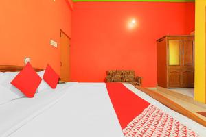 Schlafzimmer mit orangefarbenen Wänden und einem Bett mit roten Kissen in der Unterkunft OYO Flagship 86687 Hotel Anandlok in Haldwani-Kathgodam