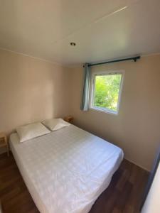 ein Schlafzimmer mit einem weißen Bett und einem Fenster in der Unterkunft Camping Val Saint Jean in Mauriac