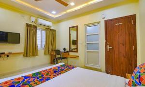 a bedroom with a bed and a desk in it at FabExpress Purple Suites Inn in Bangalore
