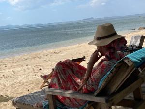 a woman sitting in a chair on the beach at Kohjum Relax Beach in Ko Jum