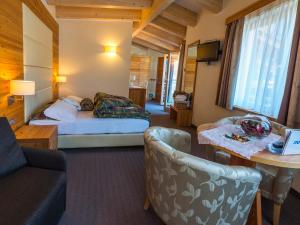 Habitación de hotel con cama y sofá en Bio Hotel Brusago Vital & Wellness en Bedollo