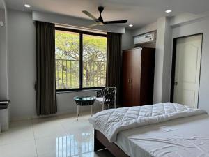 a bedroom with a bed with a ceiling fan and a window at Balaji Inn Guest House, Panjim in Panaji