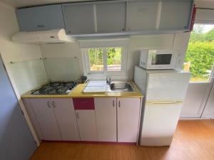 a small kitchen with a sink and a microwave at Camping Val Saint Jean in Mauriac +35 photos