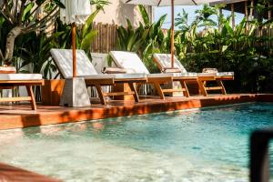 een zwembad met stoelen en tafels en een parasol bij Hijau Villa by EVDEkimi Ubud in Ubud