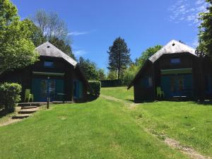 two small cottages on a green field with trees at Camping Val Saint Jean in Mauriac