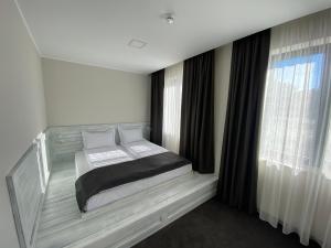 een slaapkamer met een bed in een kamer met ramen bij Комплекс Дунав in Ruse