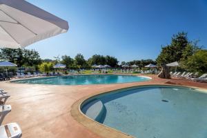una piscina con sedie e ombrelloni in un resort di Camping les Cigales Rocamadour a Rocamadour