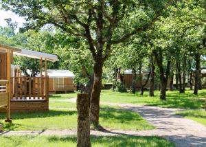 un parc avec un arbre et un bâtiment dans l'établissement Camping les Cigales Rocamadour, à Rocamadour