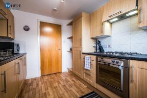 uma cozinha com armários de madeira e um fogão em Warm 3 bed Apartment Aberdeen em Aberdeen