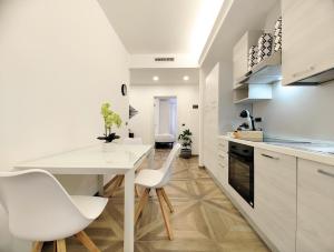 a white kitchen with white chairs and a table at Trieste Stazione - Suite & WiFi in Trieste