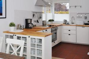 Una cocina con gabinetes blancos y una encimera de madera. en Landhaus Gericke, en Kappeln