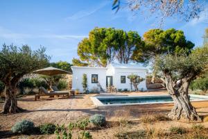 una casa bianca con piscina e alberi di CAP Menorca Relais & Chateaux a Son Bou