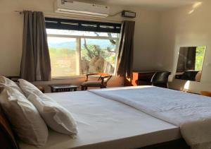 a bedroom with a large white bed with a window at The Sojourn in Dharamshala