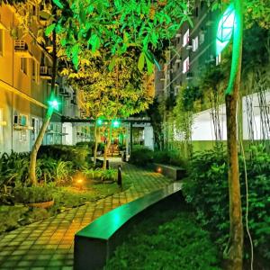 un jardín por la noche con un banco y árboles en Amaze365 Holiday Homes Condotel at Trees Residence Fairview en Manila