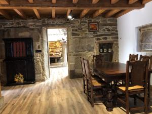ein Esszimmer mit einem Holztisch und einer Steinwand in der Unterkunft O LAR in Mazaricos