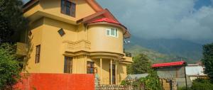 una casa amarilla con una valla roja delante de ella en The Sojourn en Dharamshala
