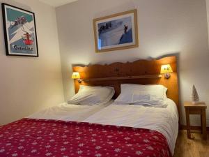 Schlafzimmer mit einem Bett mit einer roten und weißen Bettdecke in der Unterkunft Chamrousse, pied d'une piste, terrasse vue sapins in Chamrousse