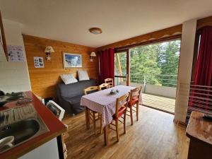 eine Küche und ein Wohnzimmer mit einem Tisch und einem Sofa in der Unterkunft Chamrousse, pied d'une piste, terrasse vue sapins in Chamrousse