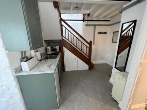 a small kitchen with a sink and a staircase at The Dog House, Mere in Mere