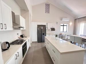 a kitchen with white cabinets and a stove top oven at Narina Villa in Victoria Falls