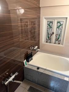 a bathroom with a tub and a glass shower at City Hotel Southern Cross in Tokyo