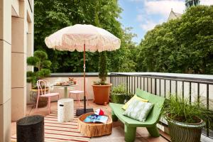 eine Terrasse mit einem Sonnenschirm, Stühlen und einem Tisch in der Unterkunft Mama Shelter Dijon in Dijon