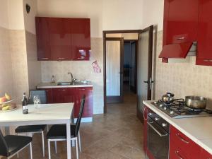 uma cozinha com armários vermelhos e uma mesa branca com cadeiras em La casa del Picchio em Vico Canavese
