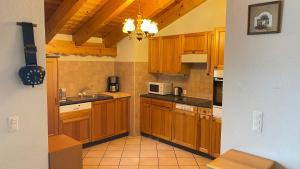 a kitchen with wooden cabinets and a chandelier at Royal 141 SKI LIFT & TERRACE apartment 8 pers by Alpvision Résidences in Veysonnaz