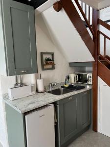 a kitchen with green cabinets and a sink at The Dog House, Mere in Mere