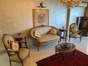 een woonkamer met stoelen, een bank en een tafel bij Sea View Luxury Apartment in Alexandrië
