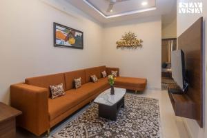 uma sala de estar com um sofá castanho e uma televisão em StayVista's Villa Orchid - Pet-Friendly Villa with Lawn, Bonfire & Indoor-Outdoor Games em Ujaim