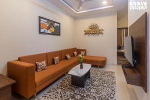 sala de estar con sofá marrón y TV en StayVista's Villa Orchid - 8 min away from Mahakaleshwar, en Ujjain
