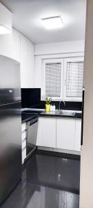 La cuisine est équipée de placards blancs et d'un réfrigérateur en acier inoxydable. dans l'établissement Bitola No. 1 Apartment, à Bitola
