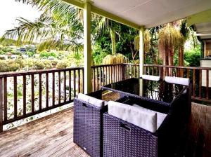 a porch with two chairs on a wooden deck at Hatea Treehouse in Whangarei