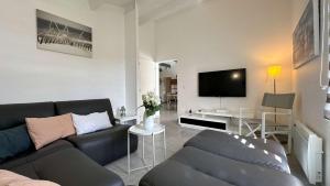 a living room with a couch and a flat screen tv at Villa avec piscine privée, à proximité de la plage et du centre de thalasso in Ars-en-Ré