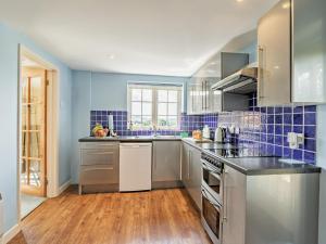a kitchen with stainless steel appliances and blue tiles at 1 Bed in Lyme Regis WHOUS in Axminster
