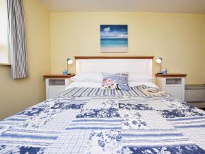 a bed with a blue and white quilt on it at 1 Bed in Lyme Regis WHOUS in Axminster