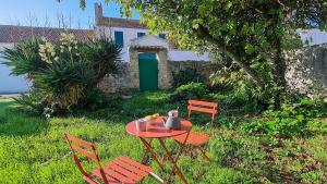a table and chairs in a yard with a green door at Jolie maison avec parking et jardin au cœur de Loix in Loix